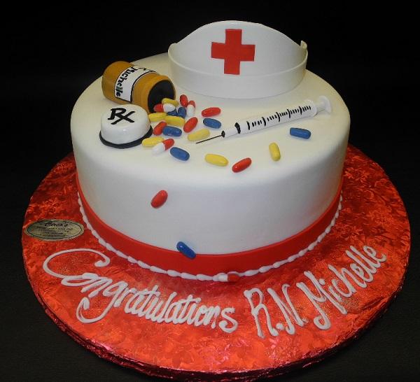 Cake by Design - 12x2 square “nurse/doctor” theme vanilla cake with  buttercream filling. Cake is covered in white fondant and detailed with  hand made decor and detailing by one of our talented